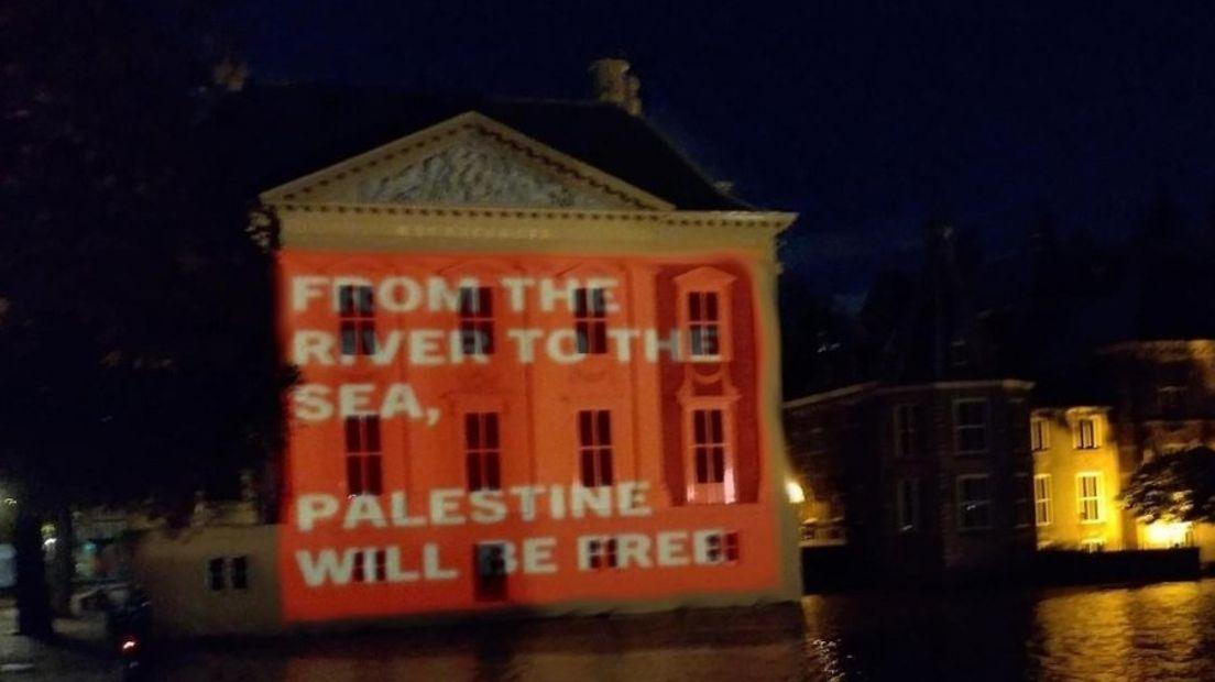 Een projectie in de avond op de gevel van het Mauritshuis in Den Haag. De geprojecteerde tekst is 'from the river to the sea, Palestine will be free'.