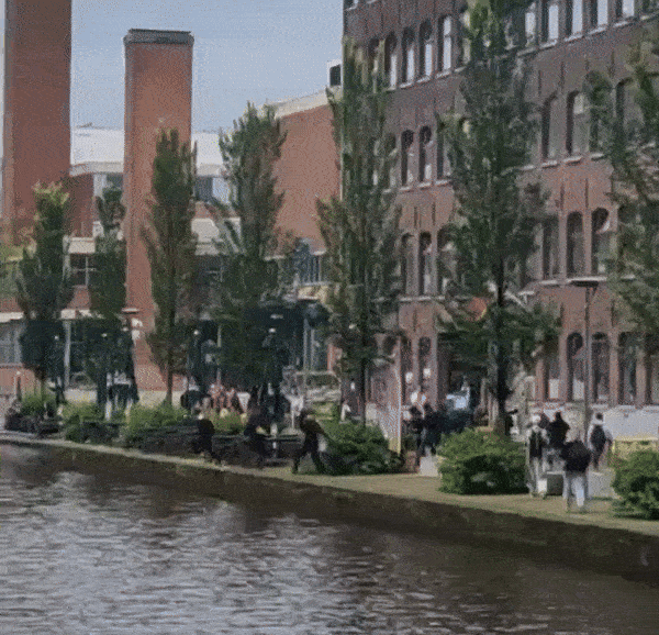 Een lage kade met daarnaast hoge bakstenen gebouwen. Een groep van ongeveer twintig mensen met keffiyeh en Palestijnse vlaggen rent weg. Verschillende personen springen in de gracht op naar de overkant te zwemmen. Vervolgens komt er een groep van ongeveer dertig agenten van de mobiele eenheid met schilden en geheven knuppels in beeld die de personen achterna zitten.